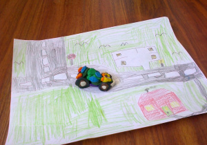 Samochód z plasteliny na kartce z narysowanym planem miasta.