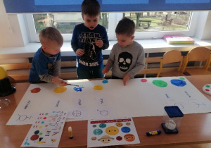 Trzech chłopców przygotowuje plakat o układzie słonecznym.