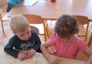 Dwoje dzieci wspólnie układa puzzle.