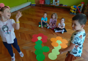 Dzieci ułożyły na podłodze kwiaty z dużych, kolorowych kół.