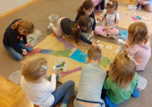 Dzieci rysują sylwetkę człowieka na dużym arkuszu papieru.