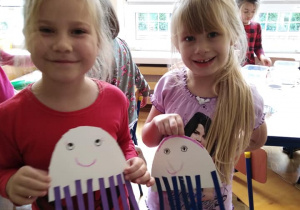 Dwie dziewczynki prezentują papierowe ośmiornice.