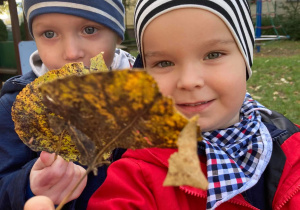 Dwóch chłopców pokazuje znaleziony jesienny liść.