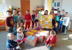 Dzieci prezentują plakat i spakowane do pudełek dary.