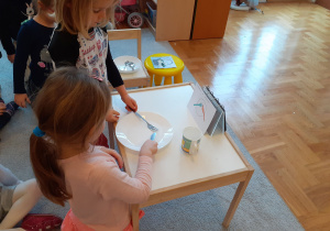 Dwoje dzieci układa sztućce według instrukcji.