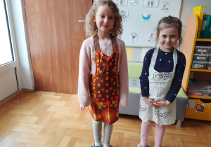 Dwie dziewczynki w fartuszkach kuchennych.