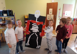 Grupa dzieci prezentuje plakat przedstawiający model szkieletu człowieka.