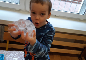 Chłopiec pokazuje bryłę lodu.