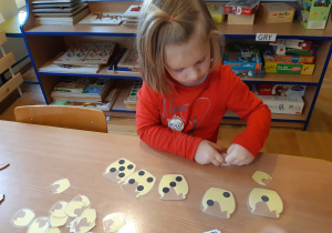 Dziewczynka układa papierowe słoiki miodu według ilości kropek.
