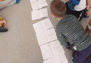Dzieci układają na dywanie napis matematyka.