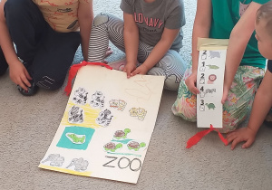 Dzieci trzymają plakat z narysowanym ZOO i nstrukcję z ilością zwierząt.