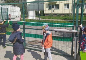 Dzieci mierzą szerokość bramy wjazdowej.