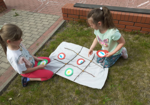 Dwie dziewczynki grają w stworzone przez dzieci kółko i krzyżyk.