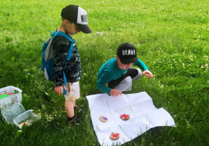 Dwaj chłopcy grają na trawie w kółko i krzyżyk.