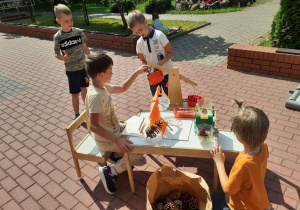Grupa dzieci bawi się wagami na tarasie.