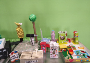 Fragment wystawy przedstawiający szatnię, magazyn leków, budynki z kopułami oraz zamknięte osiedle ze stawem i placem zabaw.