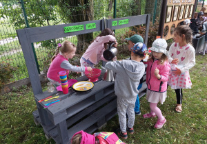 Dzieci bawią się w ogrodniczym sklepie pod chmurką.