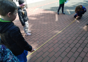 Dzieci mierzą taras za pomocą miarki.