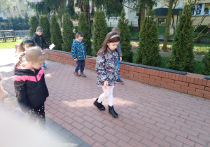 Dzieci idą wzdłuż tarasu stopa za stopą.