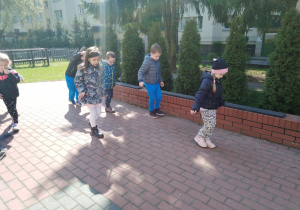 Dzieci mierzą taras idąc stopa za stopą.