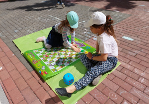 Dwie dziewczynki grają w wielkofomatową grę "Węże i drabiny".