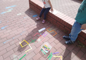 Dzieci rozwiązują łamigłówkę z kolorowych patyków.
