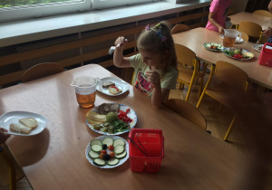 Dziewczynka komponuje kanapki podczas II śniadania w formie szwedzkiego stołu.