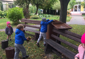 Dzieci wrzucają liście do pojemnika na bio odpady.