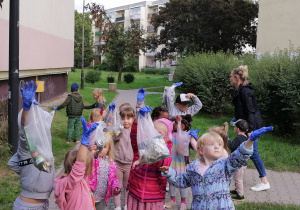 Dzieci pokazują torebki z zebranymi śmieciami.