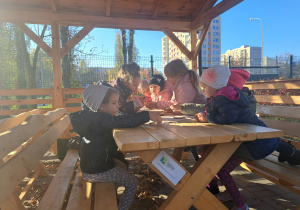 Dzieci układają puzzle przy stole w altanie.
