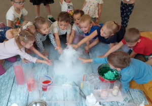 Grupa dzieci dotyka dymu wydobywającego się z pojemnika.