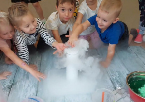Dzieci dotykają dym wydobywający się z menzurki.