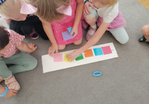 Dzieci układają kolorowe kwadraty na podkładce.