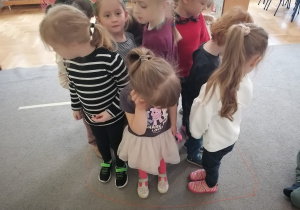 Dzieci stoją w ciasnej grupie w środku okręgu zrobionego z włóczki.
