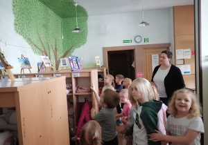 Dzieci razem z panią dyrektor oglądają w szatni wystawę zdjęć konkursowych.