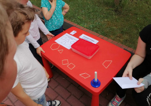 Dzieci układają na stoliku fogury geometryczne z patyczków.