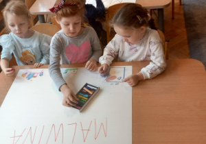 Trzy dziewczynki rysują na plakacie z imieniem Malwina.