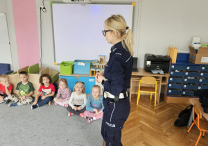 Policjantka stoi przed dziećmi.