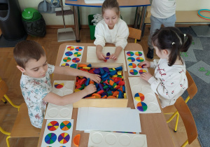 Dzieci układają klocki w kształcie ćwiartek i połówek koła według instrukcji.