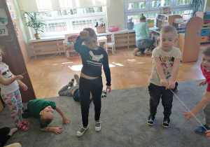 Czworo dzieci trzyma włóczkę symbolizującą linię łamaną.