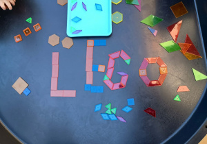 Dzieci układają z mozaiki geometrycznej napis LEGO.