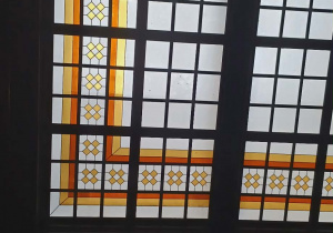 Okno witrażowe z kolorowymi kwadratami ułożonymi w linie.