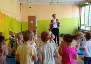 Dzieci tańczą między ławkami w sali gimnastycznej.