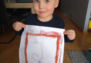 Chłopiec prezentuje swój rysunek.