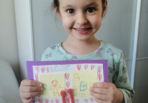 Dziewczynka prezentuje swój rysunek - herb rodziny.