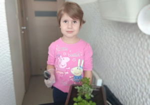 Dziewczynka prezentuje zasadzone rośliny.