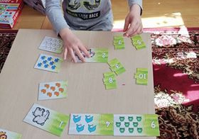 Chłopiec dopasowuje puzzle przedstawiające liczbę i ilość elementów.