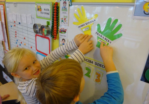 Dwoje dzieci wskazuje na kolorowe oznaczenia "Prawej Ręki" i "Dobrego Kolegi"