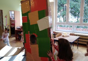 Dziewczynka okleja dużą kartonową rakietę w ramach projektu w kąciku twórczości.